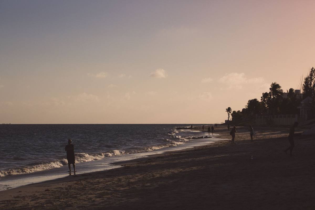 People walking along a beach at sunset