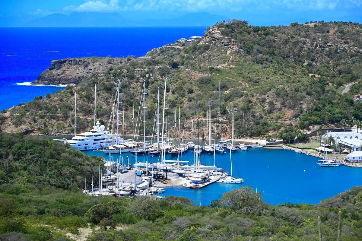 A harbour of moored yachts below green hills