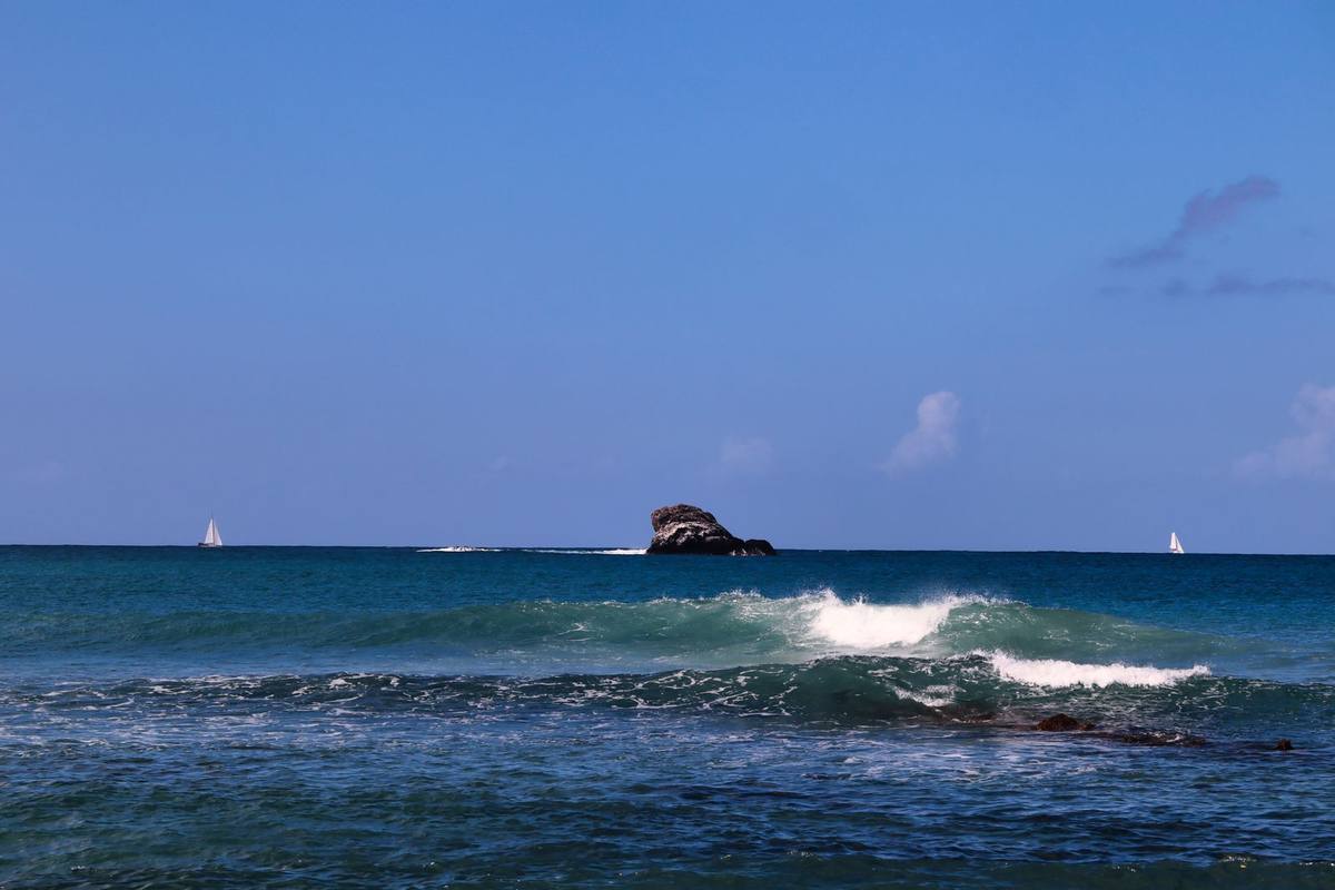 Sailboats and waves on the rocky Saint Lucia shore